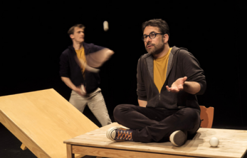 Photo du spectacle L'envers de nos décors de Clément Dazin et Thomas Scotto. Deux hommes sont sur des tables en pin avec des boules de jonglages.